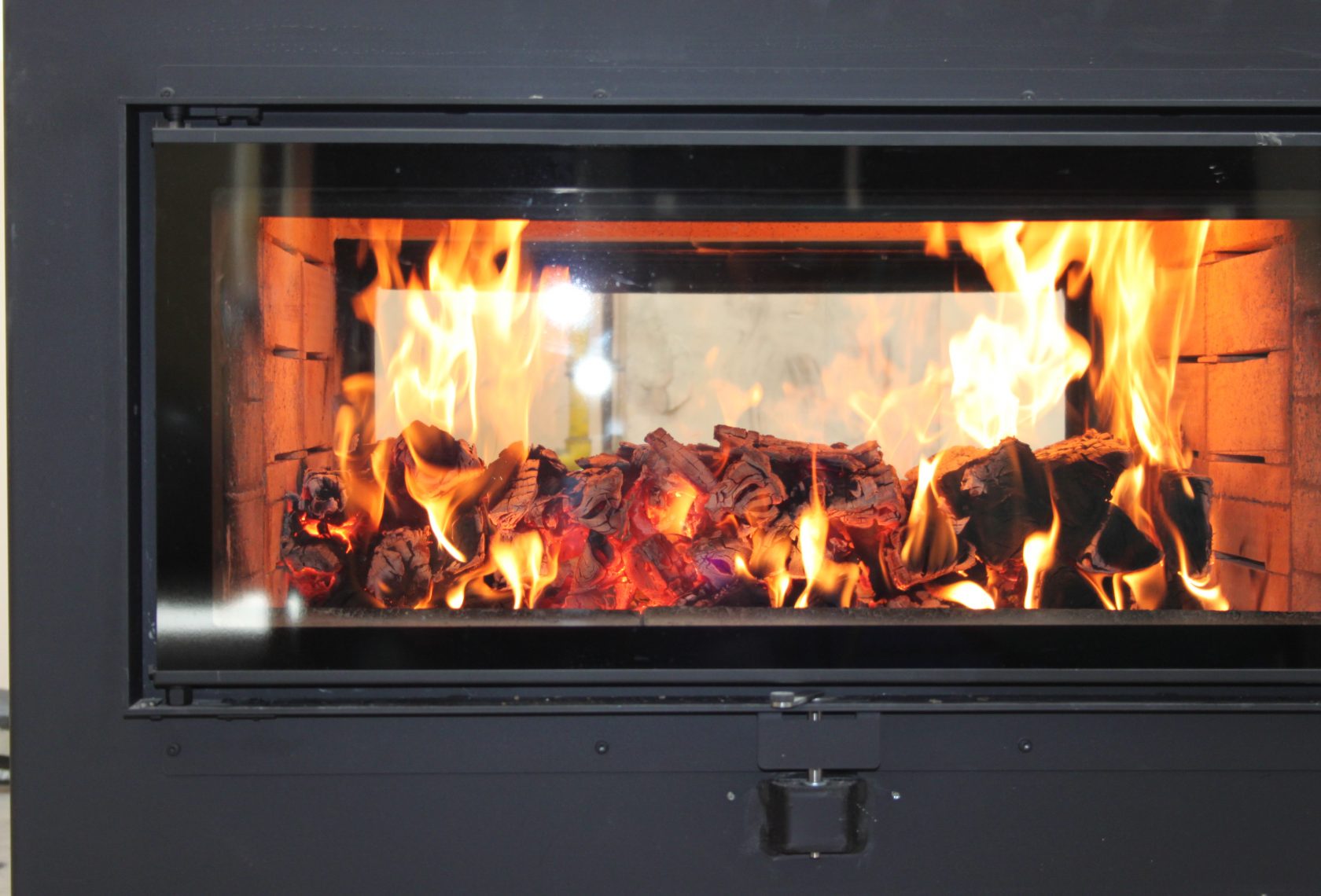 Blick durch das Kachelofenfenster auf brennendes Holz