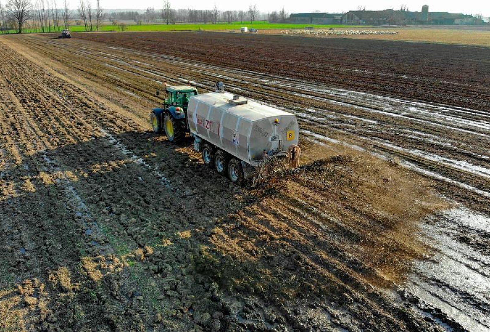 Traktor mit Anhänger verteilt Düngemittel auf dem Feld