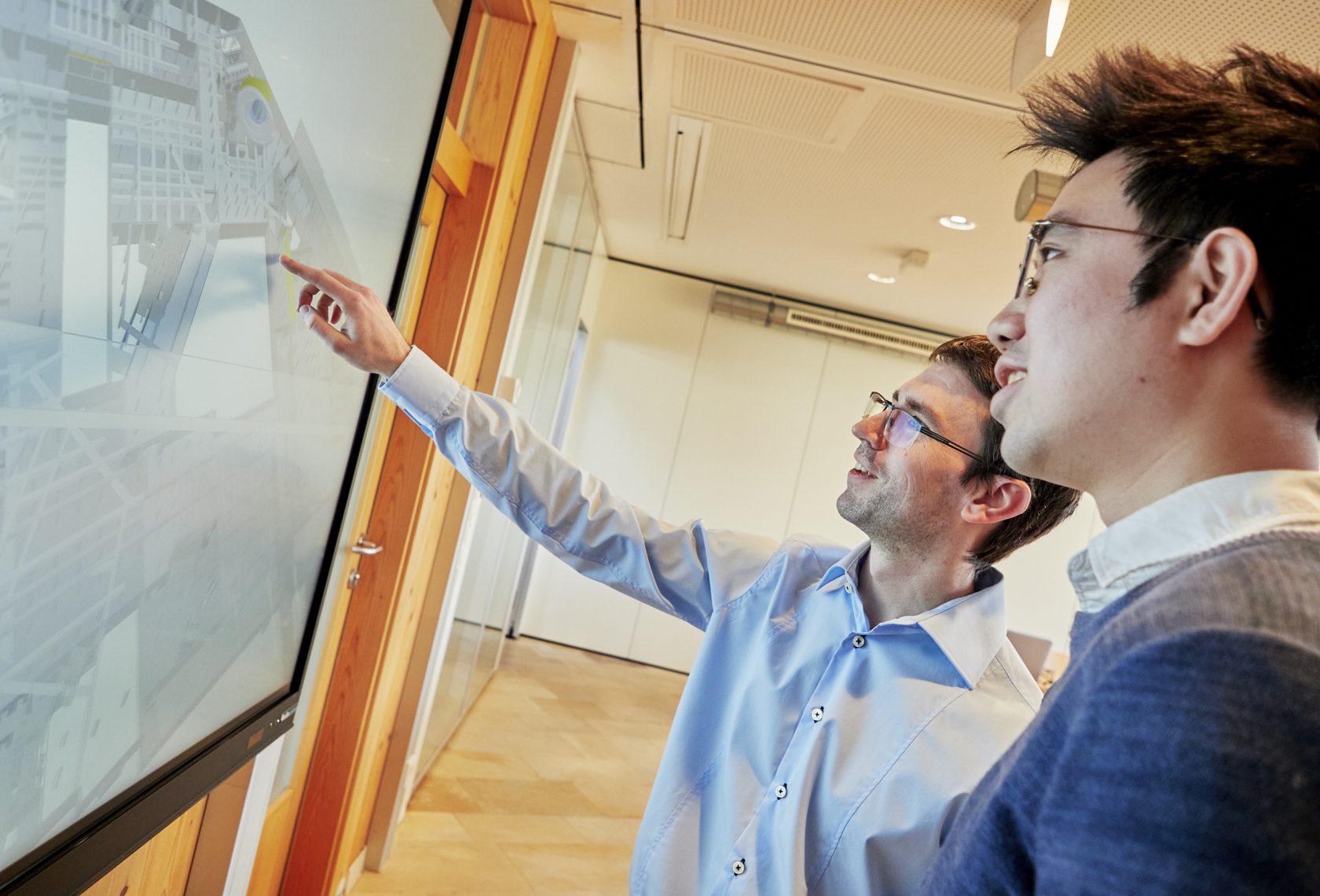 2 Personen im Gespräch vor einer Leinwand
