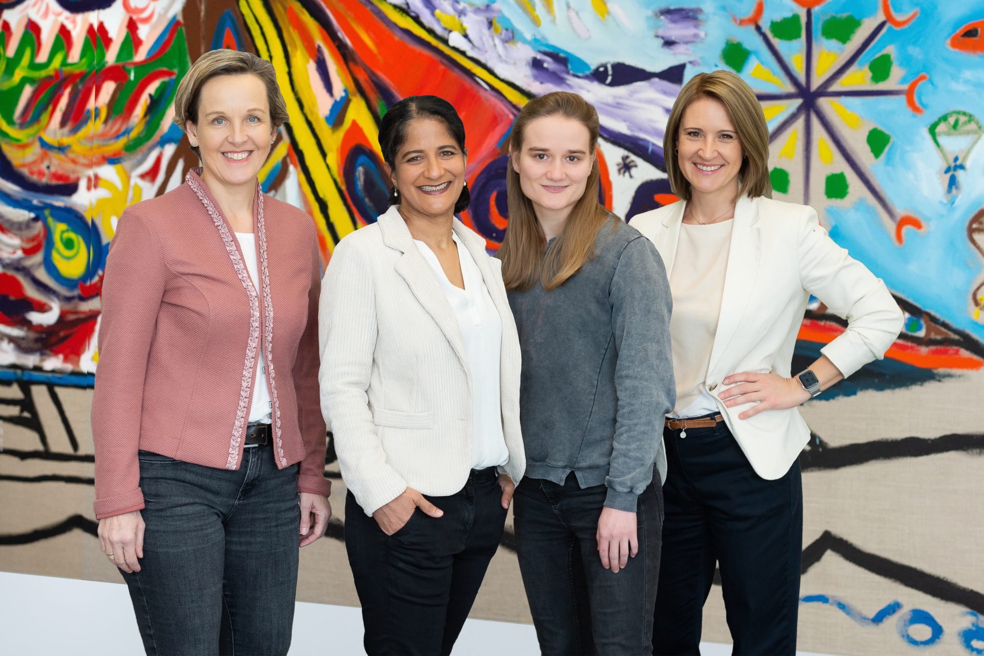 Gruppenbild von vier Personen vor einer bunten Wand
