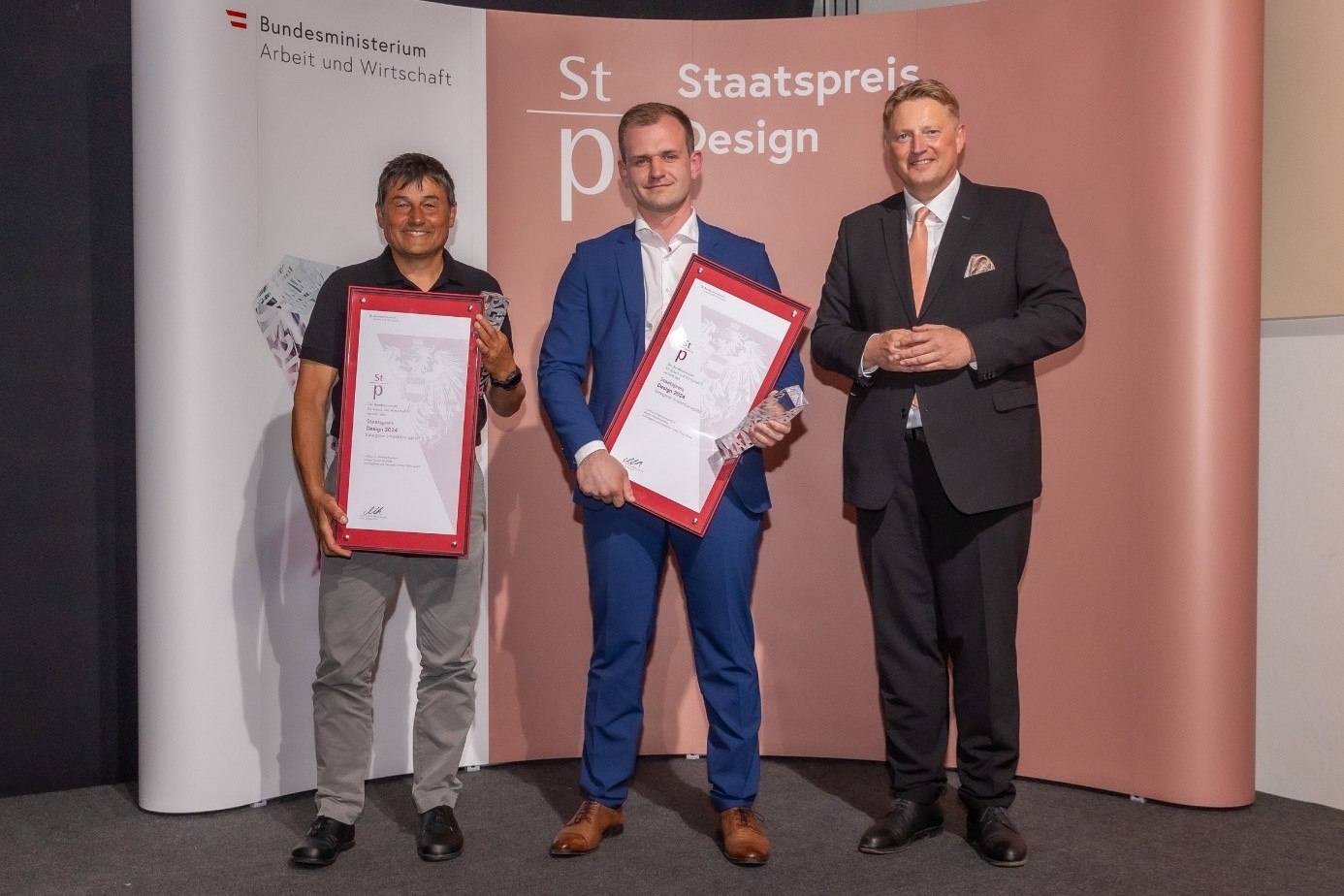 Drei Männer auf einer Bühne im Rahmen einer Preisverleihung