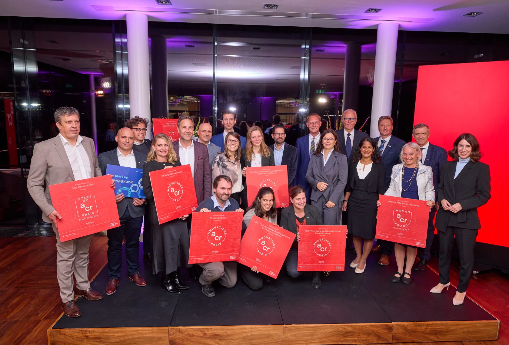 Gruppe von Personen auf dem Podium mit roten Preisschildern