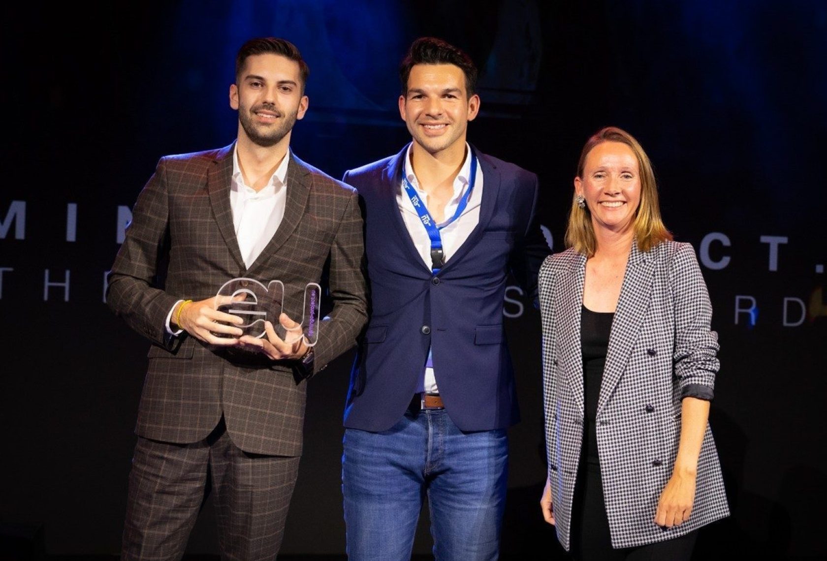 Drei Personen auf der Bühne bei einer Preisverleihung