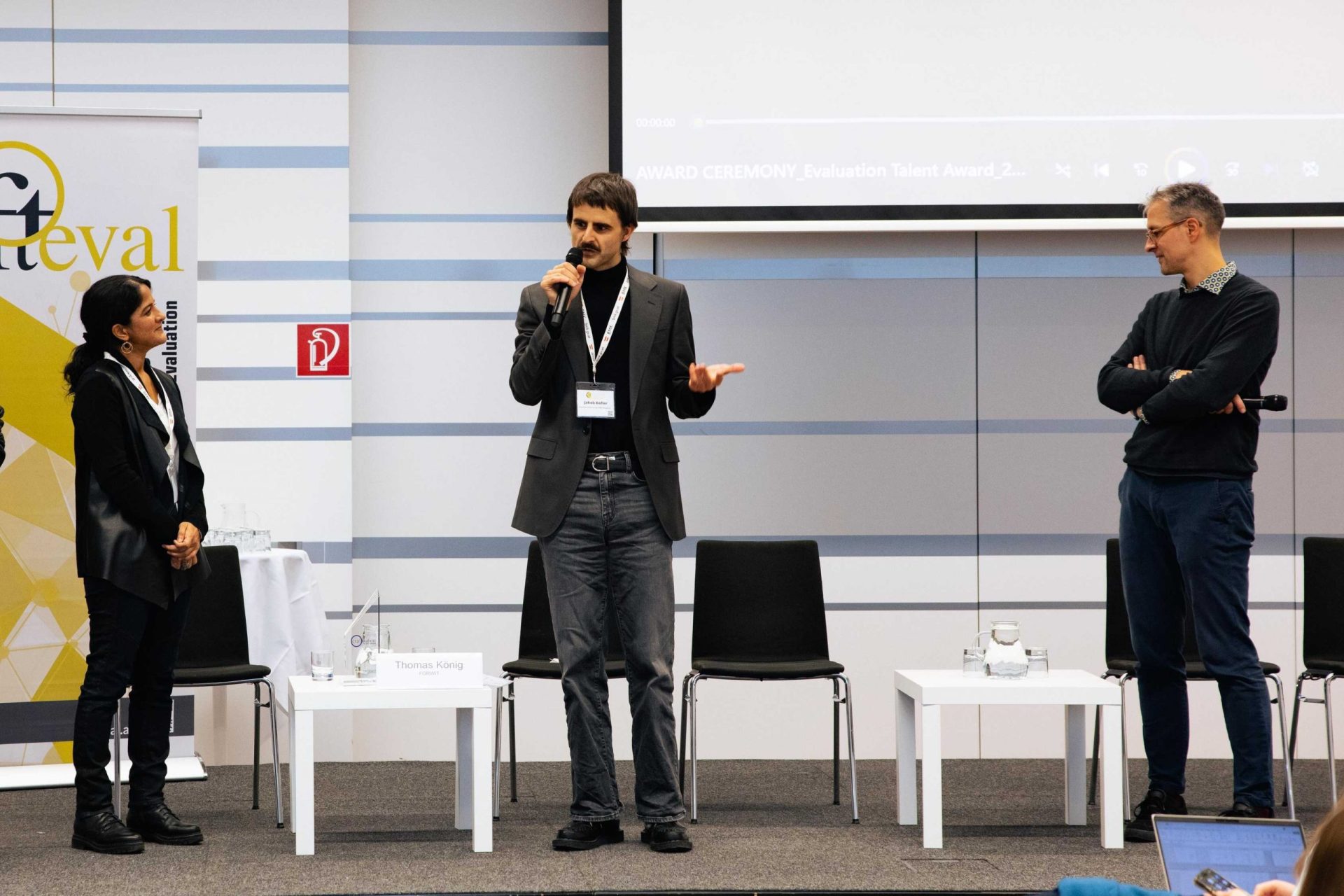 Drei Personen auf der Bühne im Rahmen einer Preisverleihung