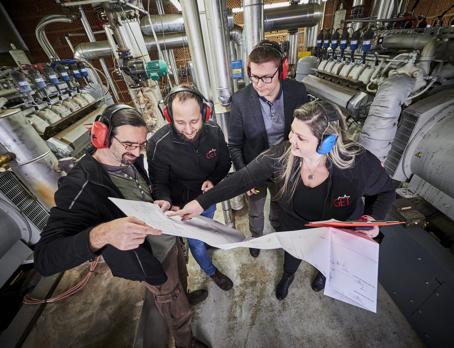 Vier Personen im Gespräch mit Blick auf einen großen Plan