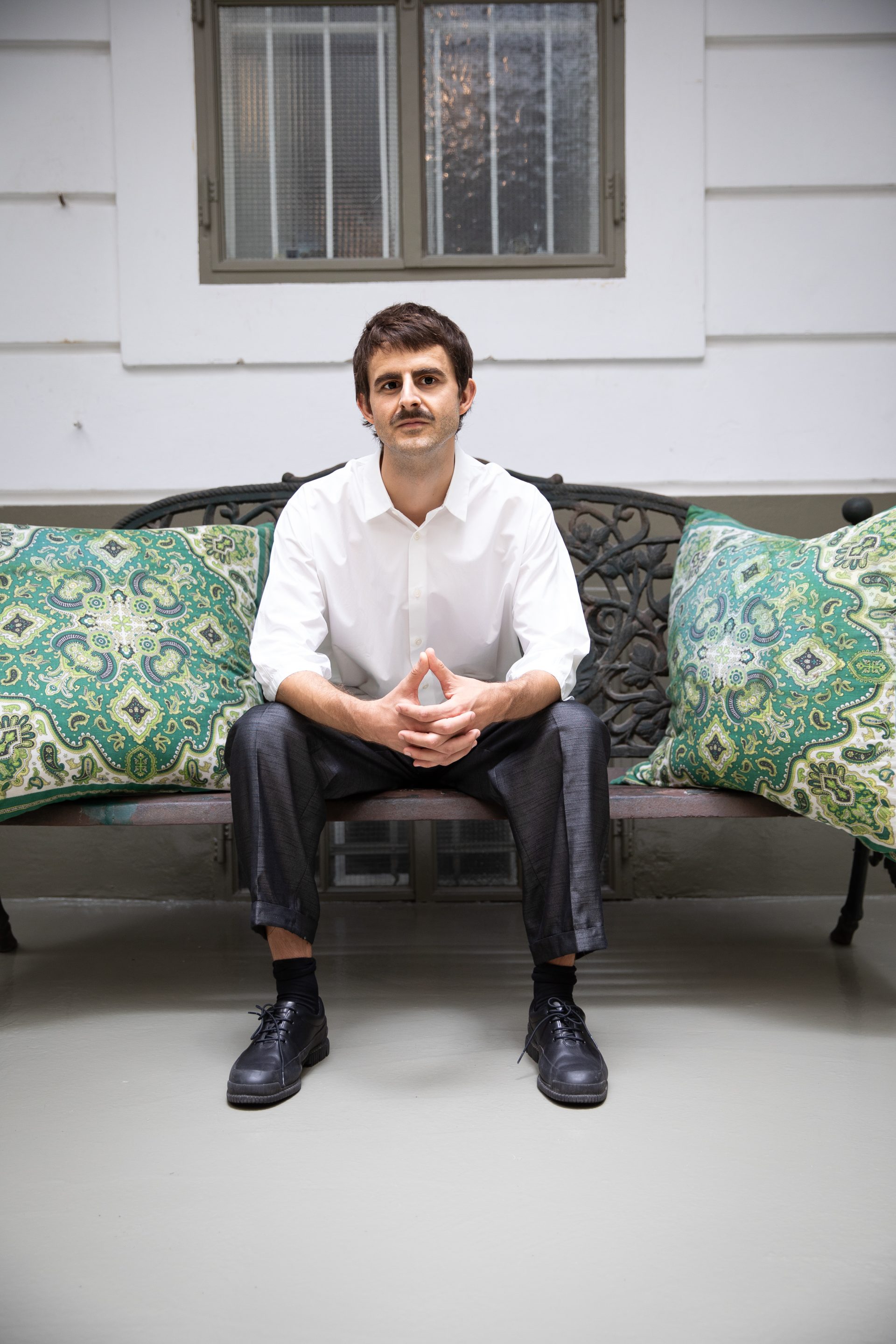 Mann sitzt auf einer Couch und sieht in die Kamera