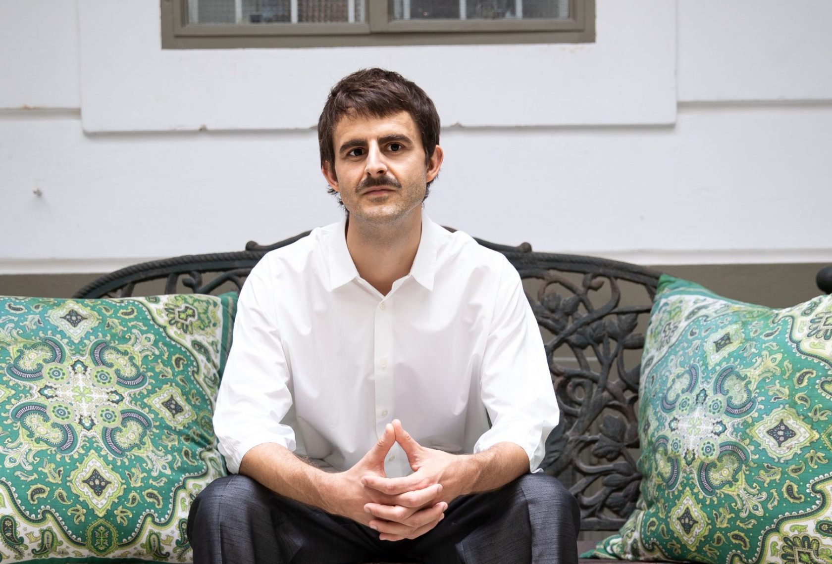 Mann sitzt auf einer Couch und sieht in die Kamera