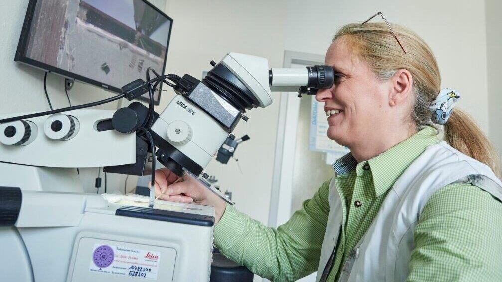 Forscherin an einem Mikroskop