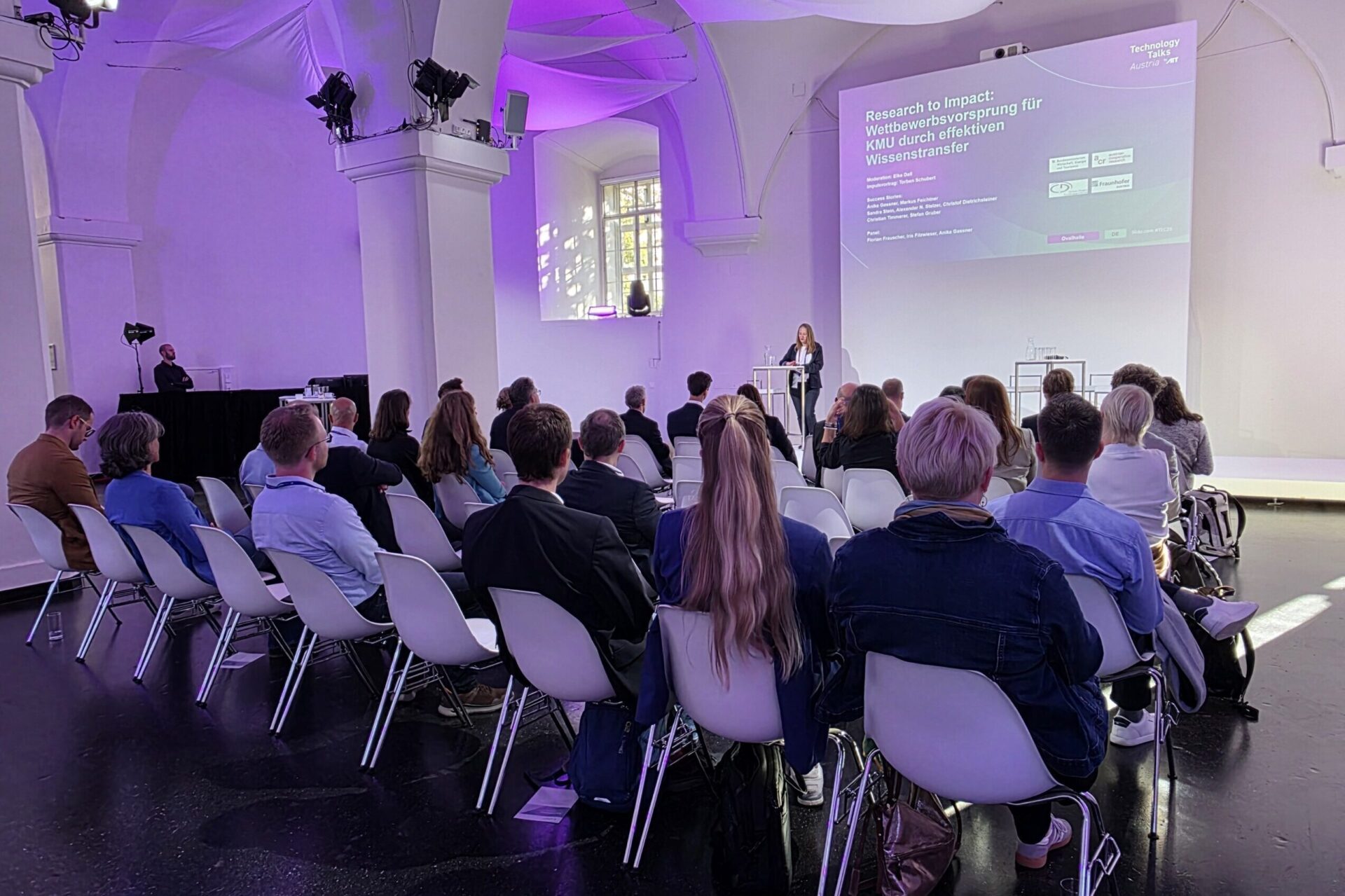 Veranstaltungssaal mit gefüllten Sitzreihen und Leinwand