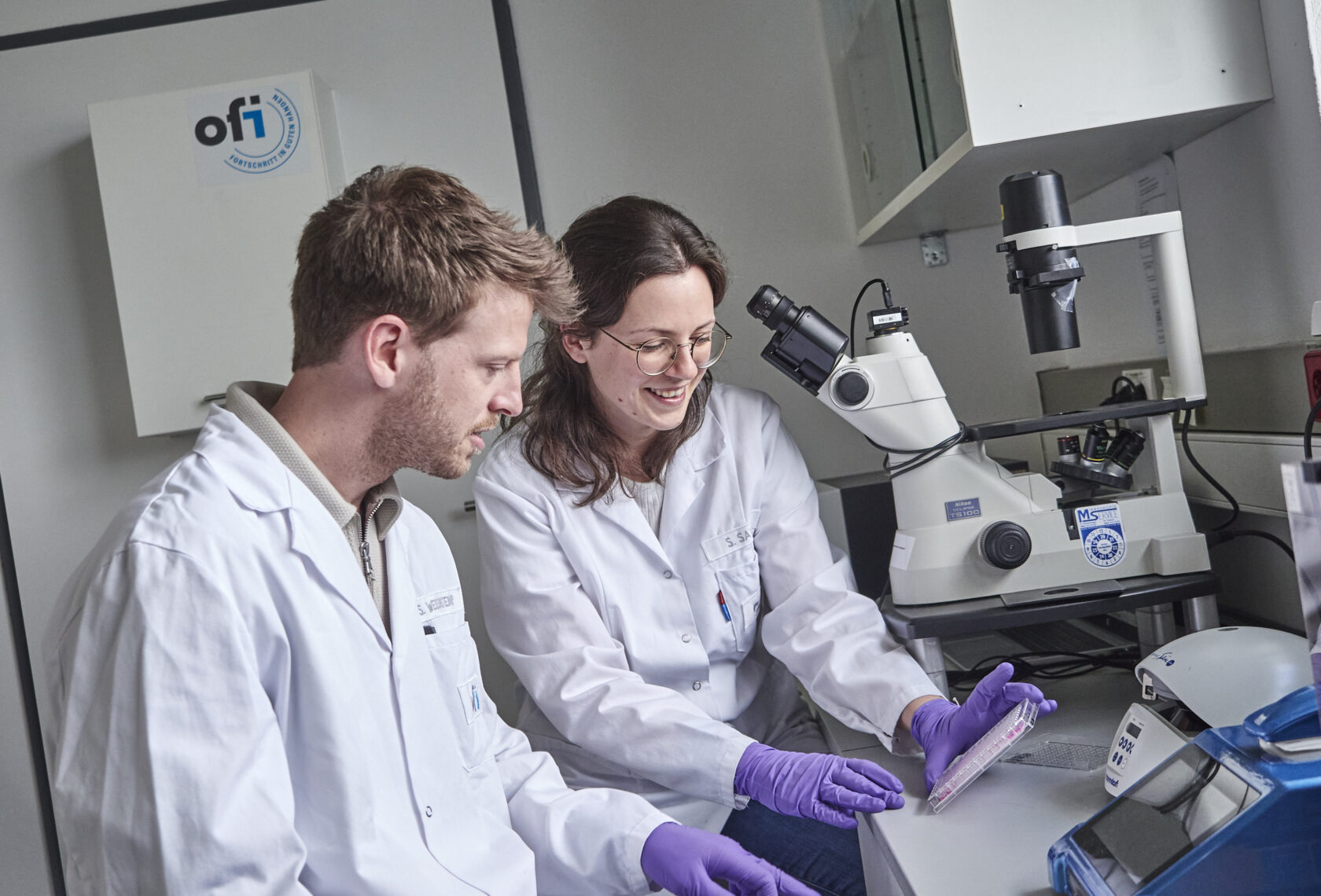 Ein Forscher und eine Forscherin vor einem Mikroskop im Labor