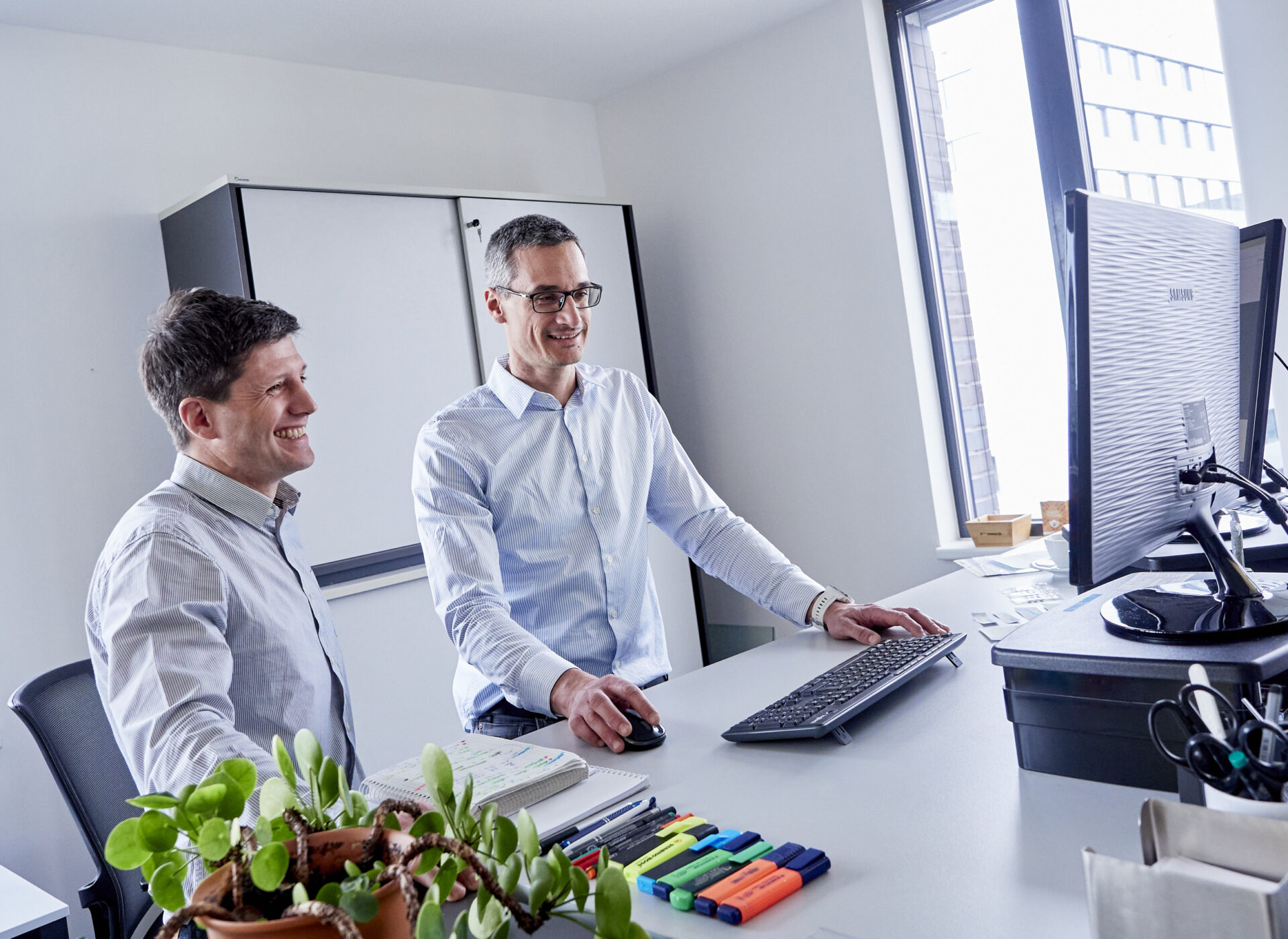 Zwei Männer im Gespräch mit Blick auf einen Bildschirm