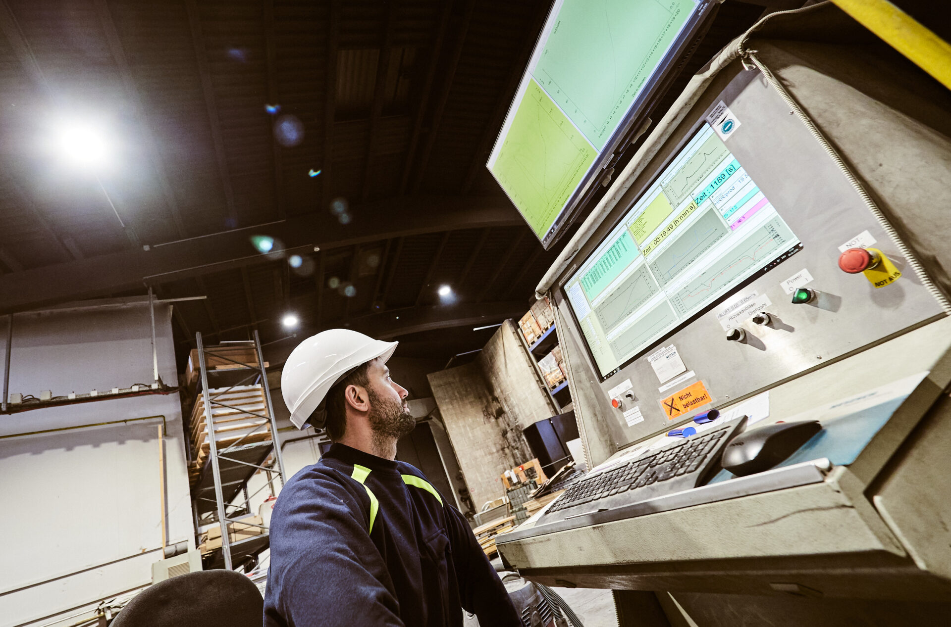 Mann mit Helm mit Blick auf einen Computerbildschirm