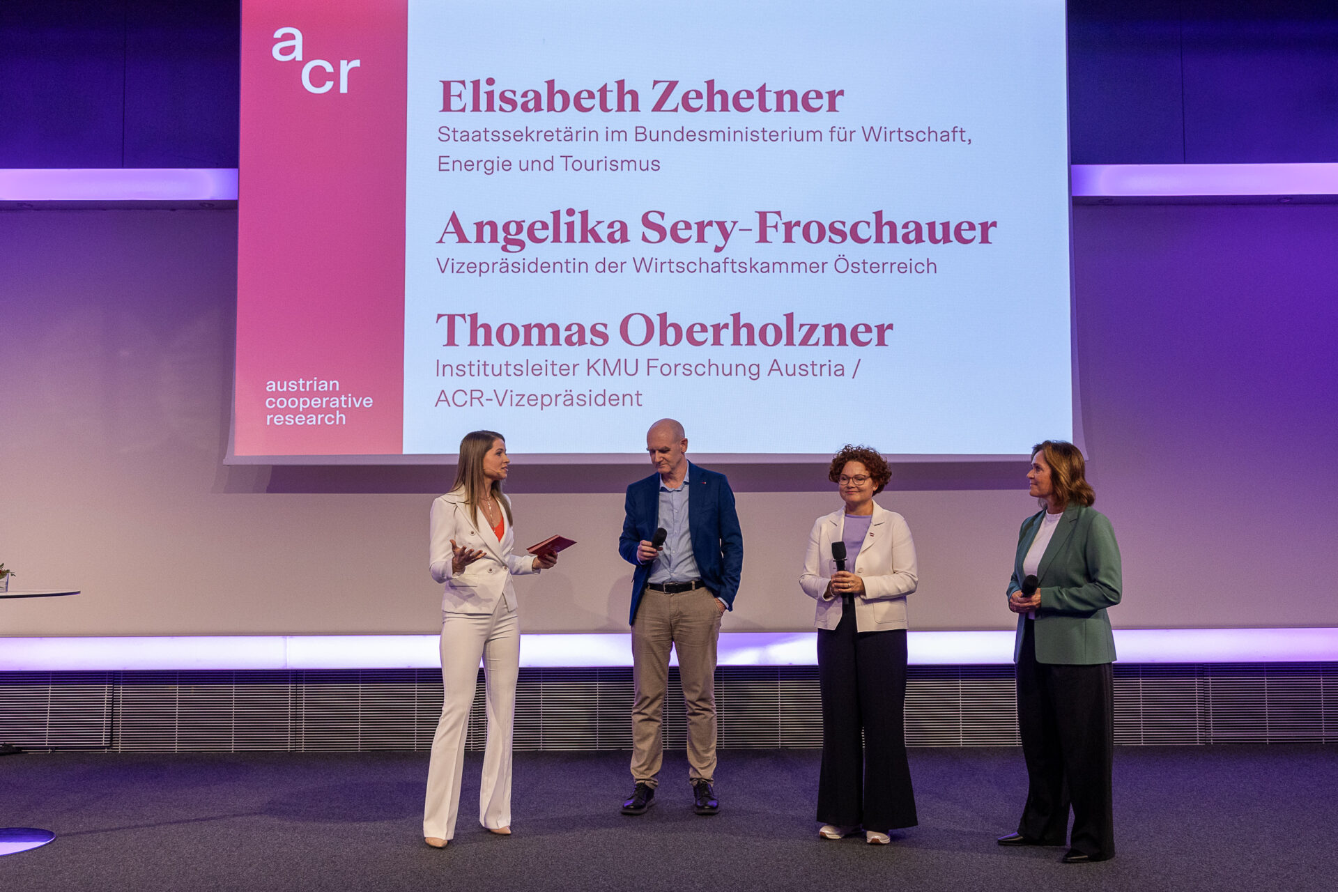 Vier Personen auf einer Bühne im Rahmen einer Podiumsdiskussion