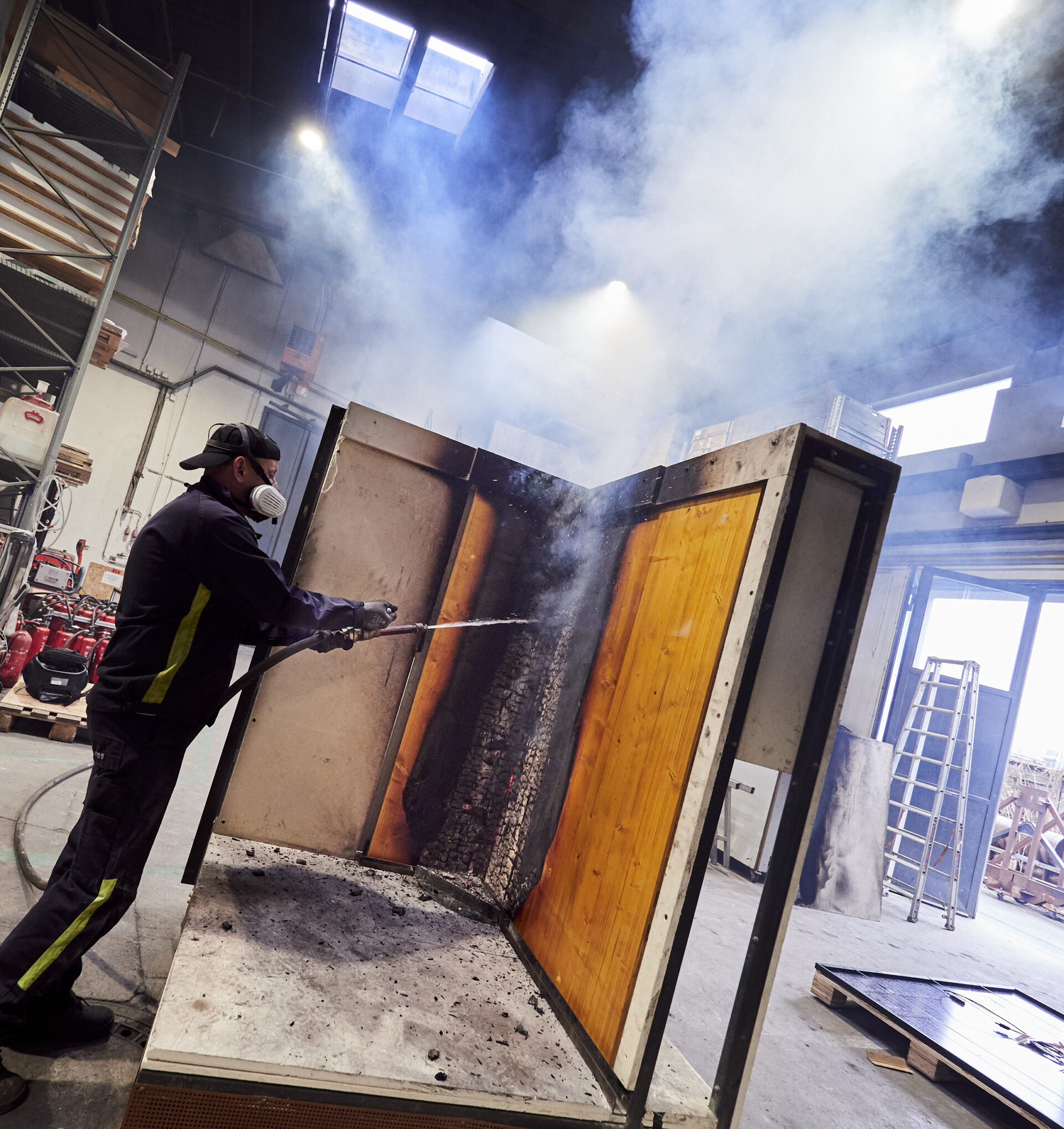 Mann beim Löschen eines brennenden Bauteils im Rahmen einer Brandprüfung