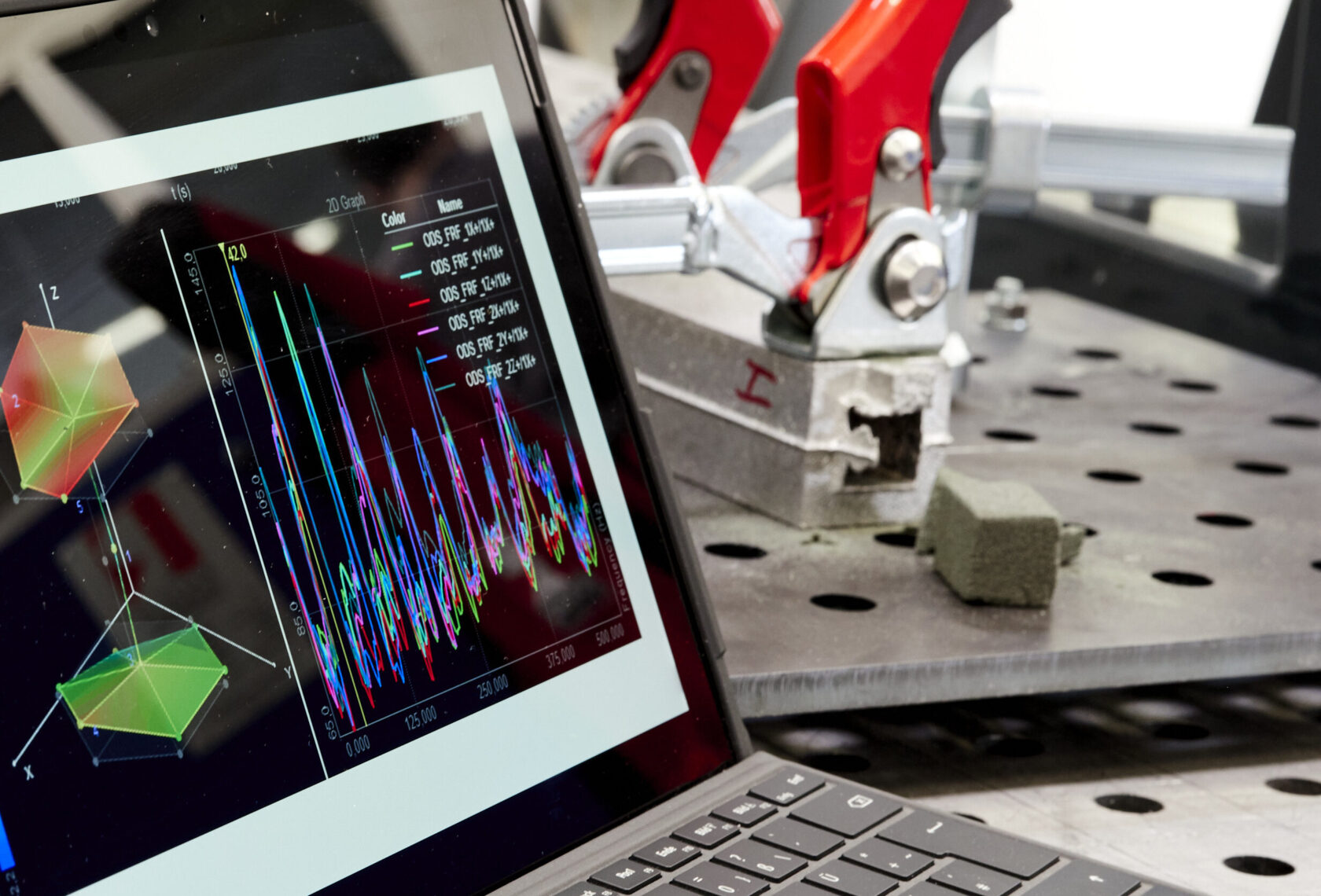 PC-Bildschirm mit Simulation im Vordergrund, Metallbauteil mit Sandkern im Hintergrund