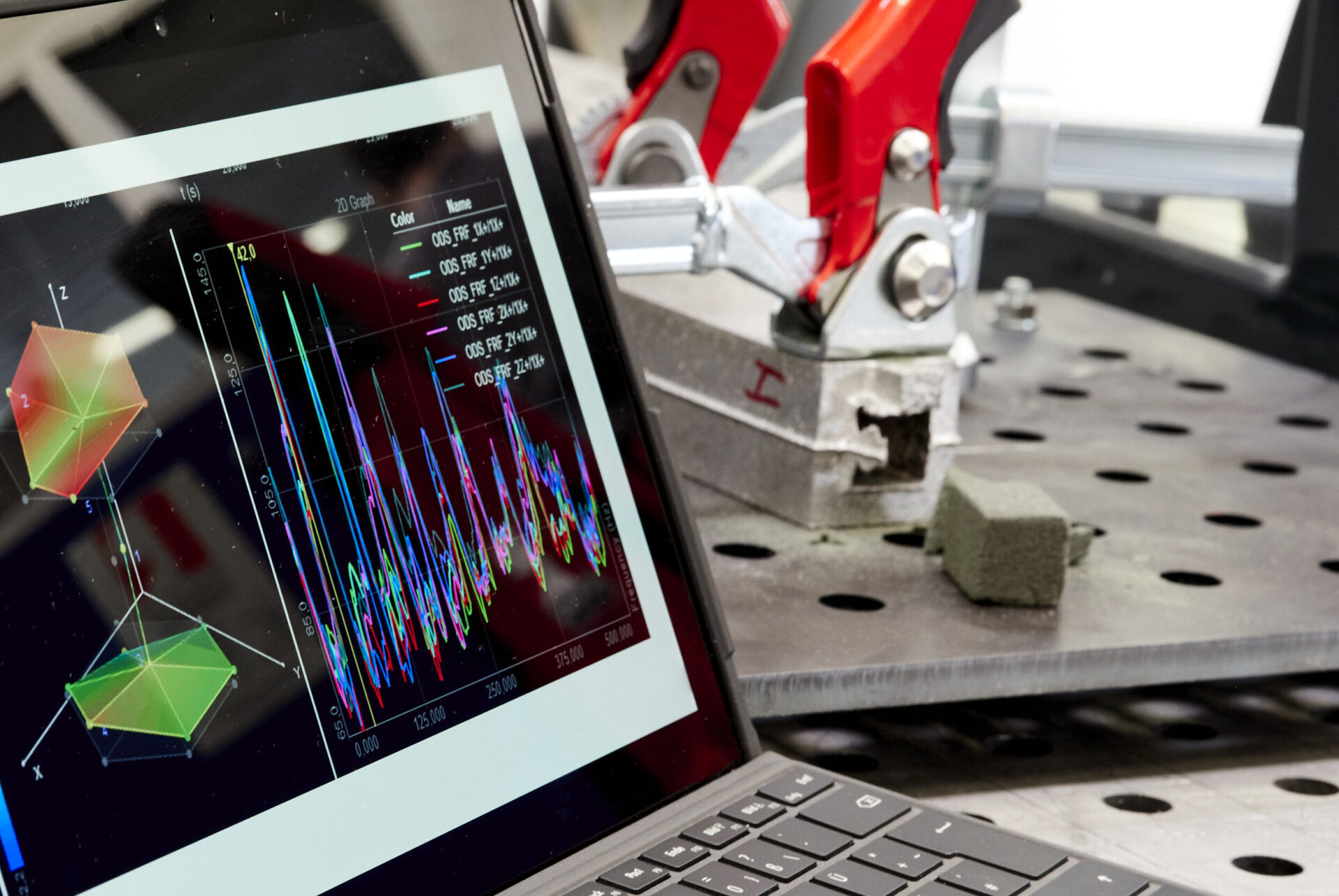 PC-Bildschirm mit Simulation im Vordergrund, Metallbauteil mit Sandkern im Hintergrund